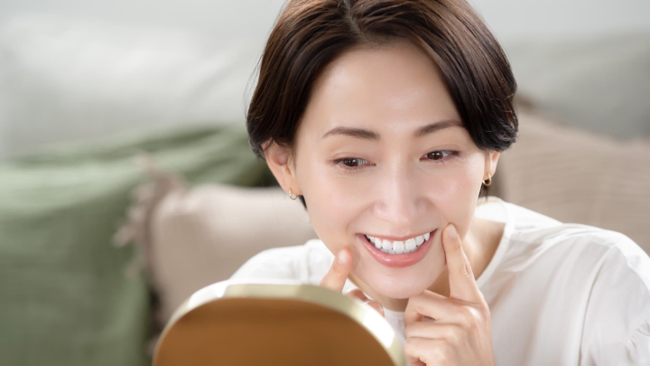 歯周病の無いきれいな歯ぐきを鏡で見て笑顔の女性