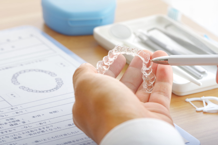 インビザライン治療中に痛みが生じる原因について説明する歯科医