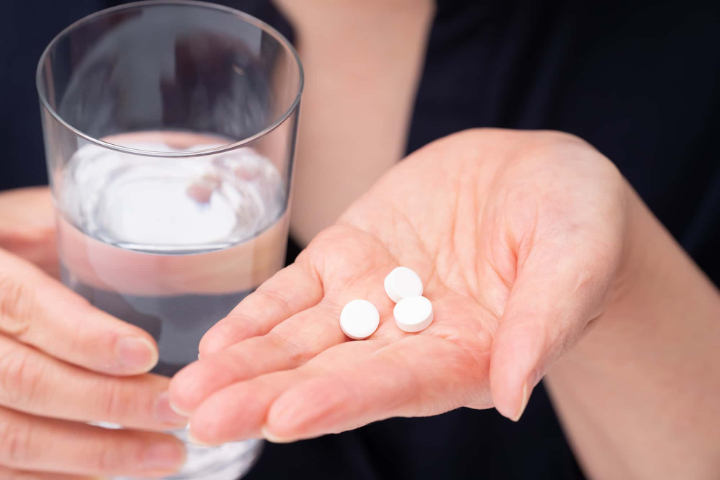 インビザライン治療中に痛みを感じて鎮痛剤を飲むイメージ