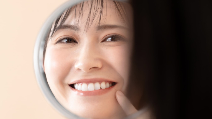 鏡で自分の歯を見ている嬉しそうな女性