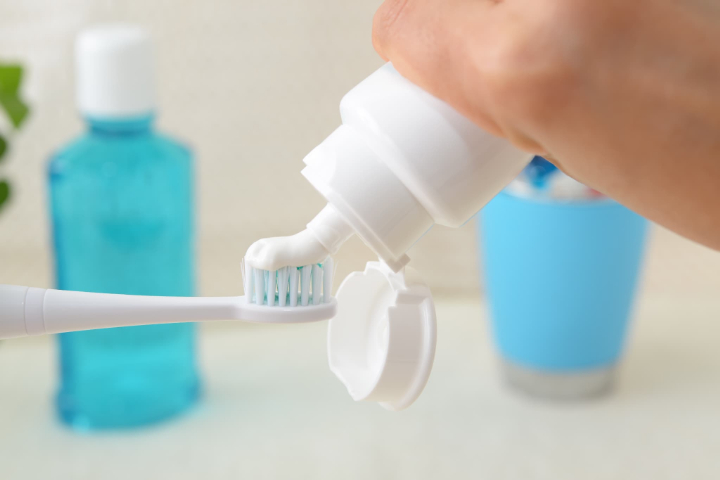 フッ素配合の歯磨き粉を歯ブラシに出す手元