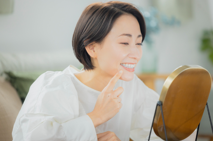 インプラント治療の仕上がりを嬉しそうに鏡で確認する女性