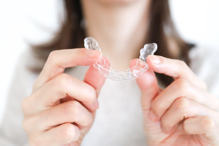 インビザラインのマウスピースを両手で持つ女性の手元