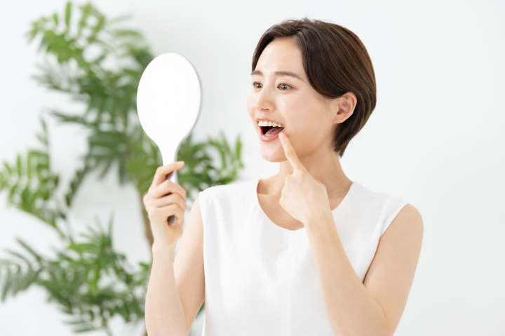 自分の歯並びを鏡でチェックする女性
