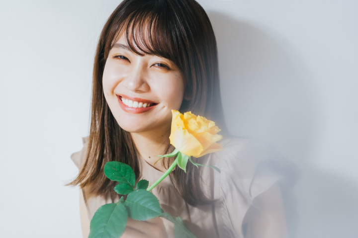 1本のバラを持ち嬉しそうに微笑む女性