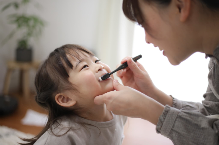 母親に仕上げ磨きしてもらう子ども