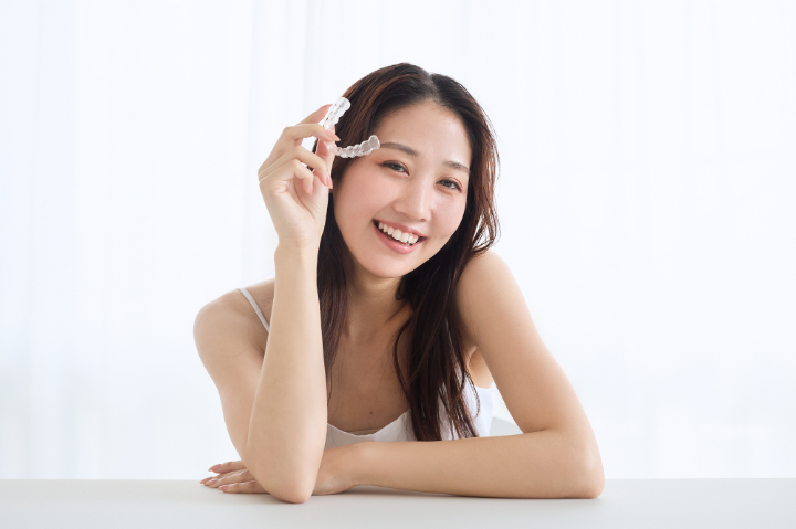 マウスピースを持って笑顔を見せる女性